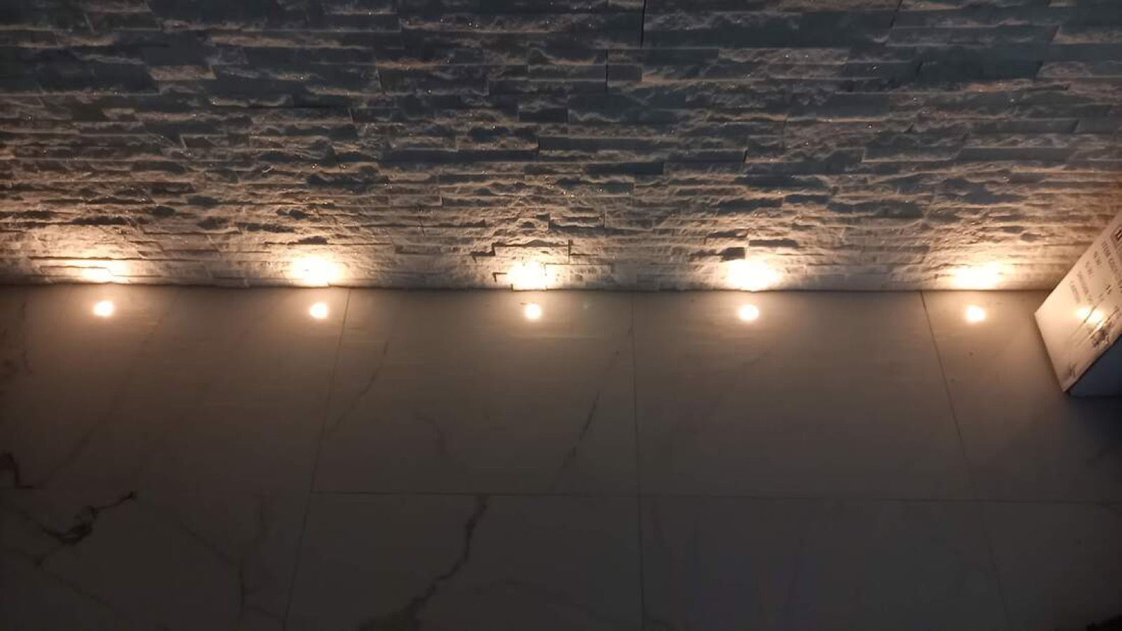 Mur en pierre éclairé par des spots encastrés au sol